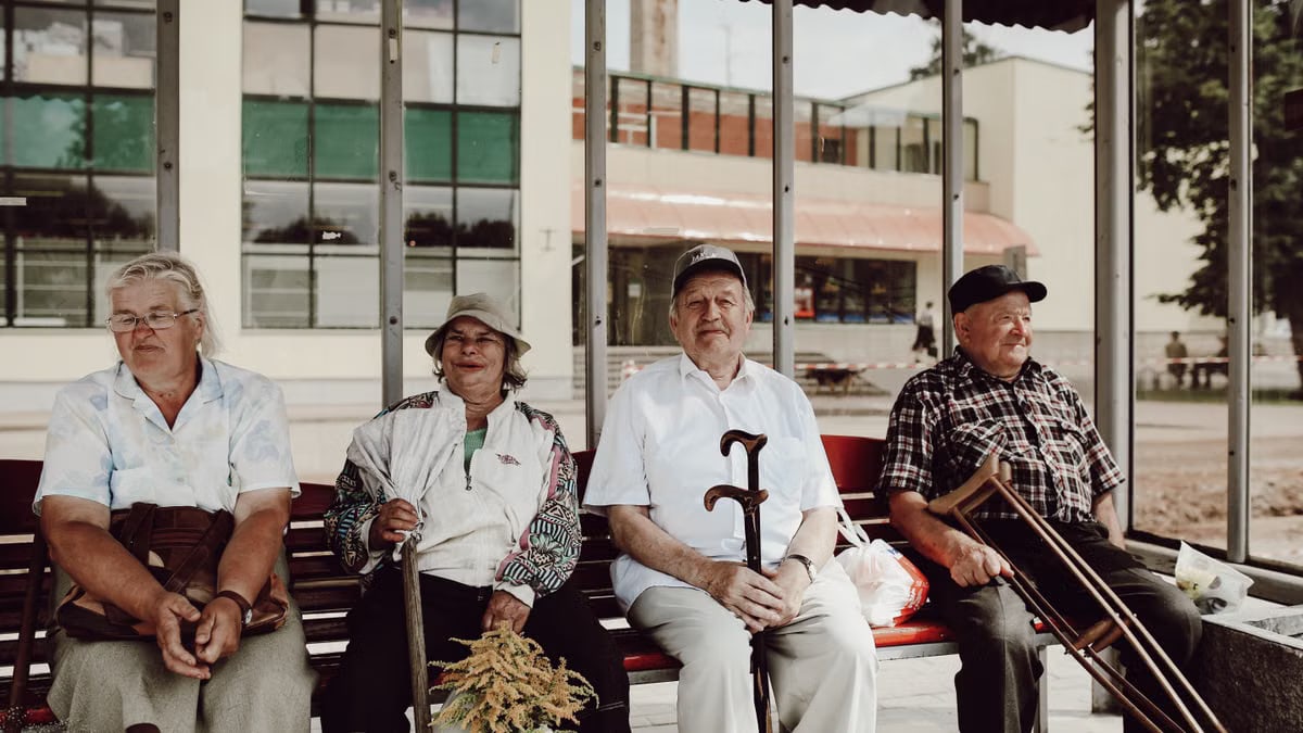 Group of seniors sitting together on a bench, enjoying a relaxed moment in an urban setting.